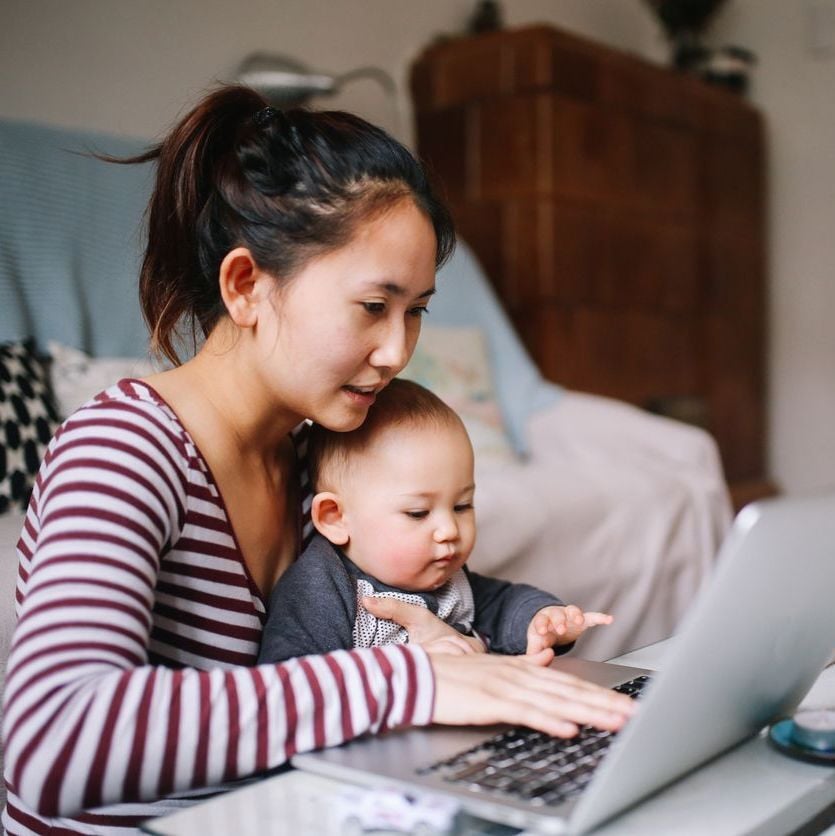 Mother on a computer with an infant on her lap