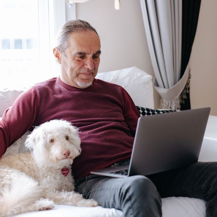 Older man and dog sitting at his laptop